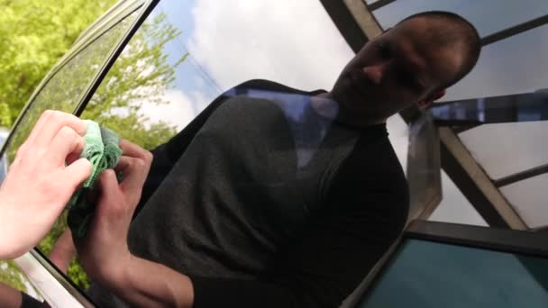 El hombre está limpiando las ventanas del coche con una alfombra en el punto de auto-lavado del coche — Vídeos de Stock