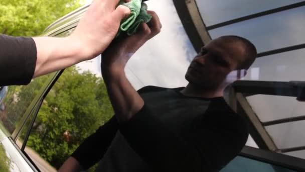 Чоловік прибирає вікна автомобіля килимком у точці автомийки — стокове відео