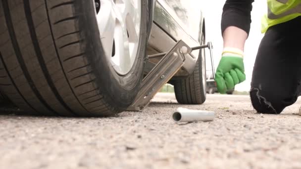 L'homme met la veste sous la voiture pour changer le pneu crevé — Video