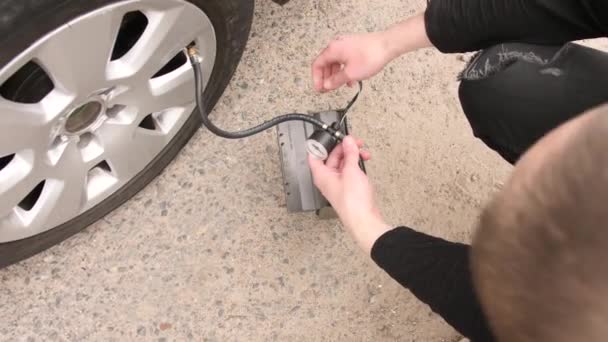 Ein Mann checkt mit einem Manometer den Reifendruck — Stockvideo