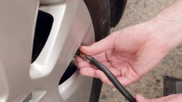 Um homem está a controlar a pressão no pneu com um manómetro. — Vídeo de Stock