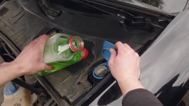 El hombre está vertiendo líquido anticongelante en un coche — Vídeos de Stock