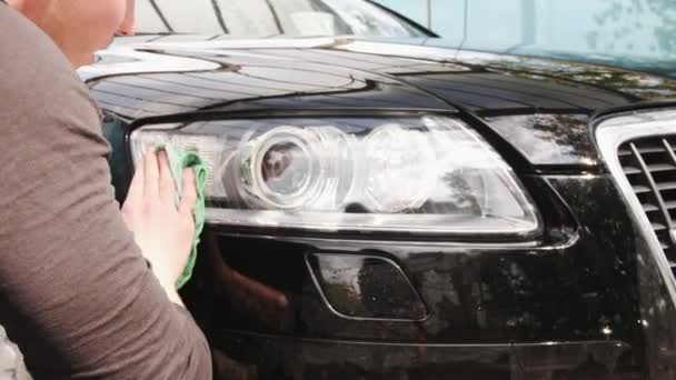 El primer plano del lavado de un coche faros iluminación de un coche negro — Vídeos de Stock