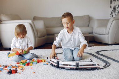 Çocuklar oyun odasında lego ve oyuncak trenle oynuyorlar.