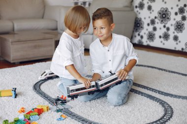 Çocuklar oyun odasında lego ve oyuncak trenle oynuyorlar.