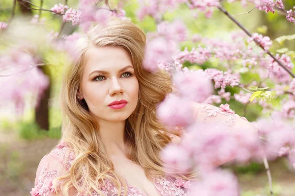 Mujer rubia joven de pie en un jardín floreciente Imagen De Stock