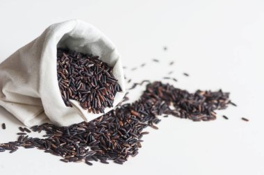 Tay jasmine siyah pirinç veya pirinç berry beyaz çuval ve kalp şekli beyaz zemin üzerine yığını.