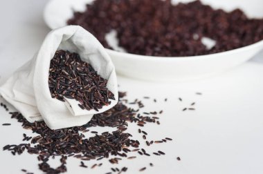 Tay jasmine siyah pirinç veya pirinç berry beyaz çuval ve kalp şekli beyaz zemin üzerine yığını.