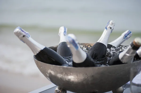 Wine bottles in ice bucket on luxury beach dinning party at sunset.