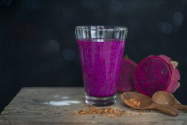 Ahşap yüzeyde kırmızı ejder meyvesi, koyu siyah arka plan, durgun yaşam tarzı.