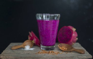 Ahşap yüzeyde kırmızı ejder meyvesi, koyu siyah arka plan, durgun yaşam tarzı.