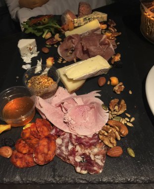Siyah taş tahtada çeşitli peynir ve fındıklı karışık sosis aperatifi..