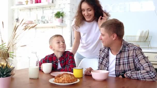 Lycklig familj mor, far och son äter frukost i köket. — Stockvideo