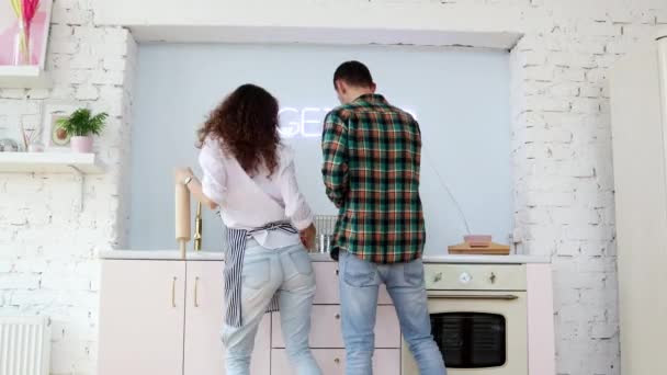 Jong vrolijk paar dansen in een keuken terwijl koken. — Stockvideo