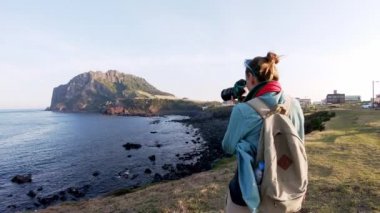 Kadın profesyonel fotoğrafçı manzaranın fotoğraflarını çekiyor.