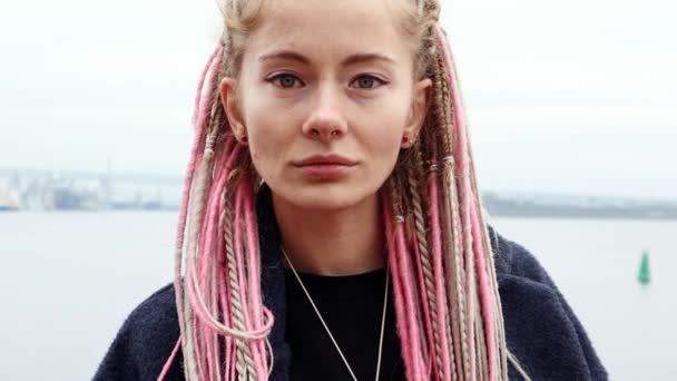 Gyönyörű fiatal görög nő piercingekkel és rózsaszín rasztákkal — Stock videók