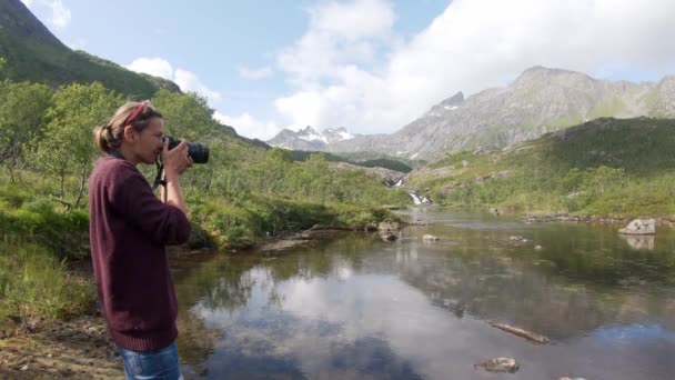 Молодая женщина-внештатный фотограф фотографирует норвежский пейзаж — стоковое видео