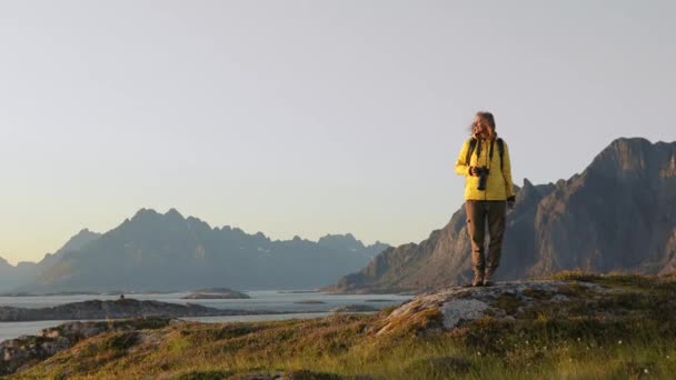 Mujer fotógrafa relajándose y disfrutando de la vista de un paisaje noruego — Vídeo de stock