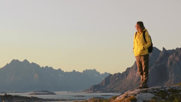 Mulher viajante relaxante e apreciando a vista da paisagem norueguesa de uma colina — Vídeo de Stock