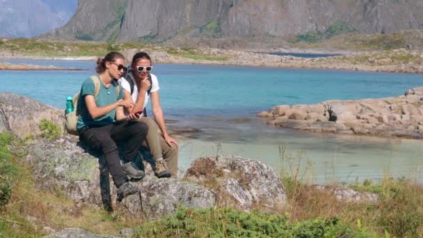 Två unga kvinnliga resenärer som använder en smartphone med utsikt över en norsk fjord — Stockvideo