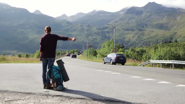 Mulher jovem carona em pé na estrada com vista para as montanhas . — Vídeo de Stock