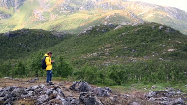Молода жінка мандрівник стоїть на горі і використовує свій смартфон — стокове відео