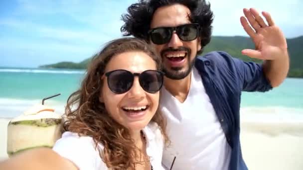 Jong vrolijk paar het nemen van een selfie op het tropische strand met een uitzicht op zee. — Stockvideo