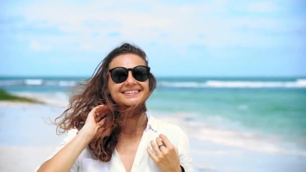 Portret van een jonge vrolijke vrouw met lang krullend haar in een zonnebril — Stockvideo