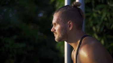An athletic man relaxing after a productive workout in the outdoor gym.