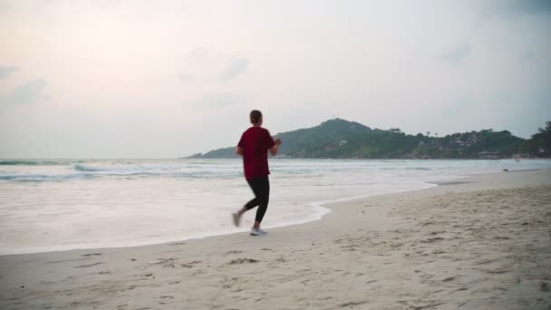 Joven mujer sana corriendo en la playa al amanecer . — Vídeos de Stock