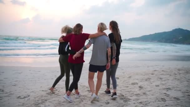 Grupa czterech młodych kobiet spacerujących po plaży o wschodzie słońca. — Wideo stockowe