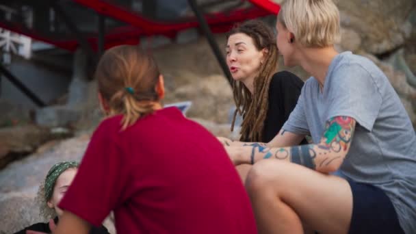 Grupo de cuatro mujeres jóvenes, mejores amigos sentados al aire libre y hablando . — Vídeos de Stock