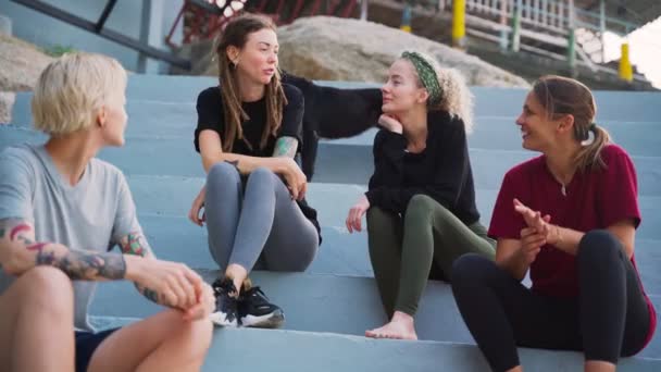 Grupo de quatro jovens mulheres, melhores amigos sentados ao ar livre e conversando . — Vídeo de Stock