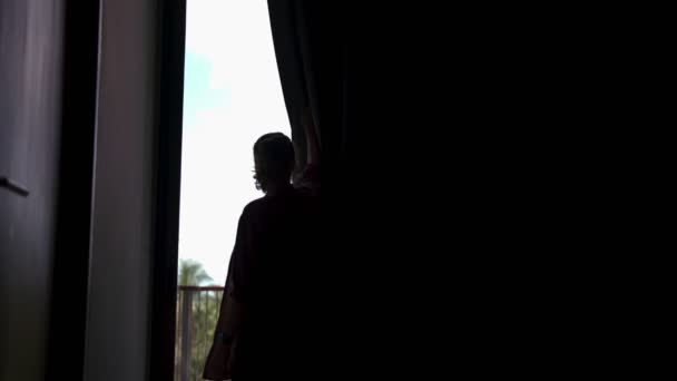 A young woman opens blackout curtains — ストック動画