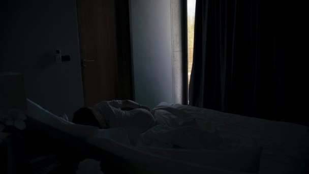 A young caucasian woman traveler wakes up and opens blackout curtains — Wideo stockowe