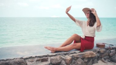 A young woman in a big straw hat taking a selfie