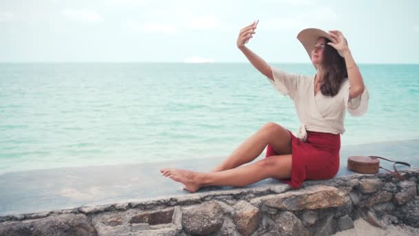 Uma jovem mulher com um grande chapéu de palha tirando uma selfie — Vídeo de Stock