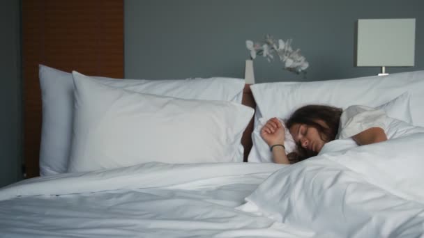 Joven mujer caucásica durmiendo en la cama en una habitación de hotel . — Vídeos de Stock