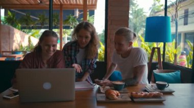 Genç iş arkadaşları dizüstü bilgisayarlar üzerinde çalışıyor ve iş konuşuyorlar.