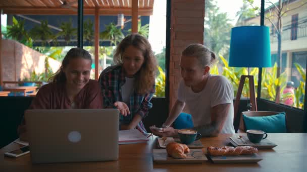 Equipo de jóvenes compañeros de trabajo trabajando en computadoras portátiles y discutiendo negocios — Vídeo de stock