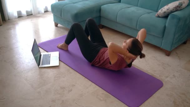 Une jeune femme séduisante faisant des exercices tout en travaillant à domicile . — Video