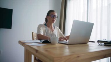 Bilgisayarını kullanarak evde çalışan genç bir bayan öğretmen.