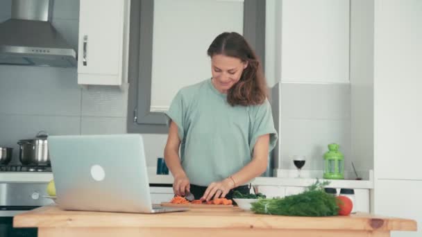 Junge Frau kocht in der Küche, während sie mit Freunden über das Internet spricht. — Stockvideo