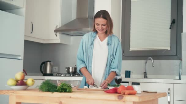 Nuori kaunis valkoihoinen nainen ruoanlaitto hänen kirkas keittiö — kuvapankkivideo