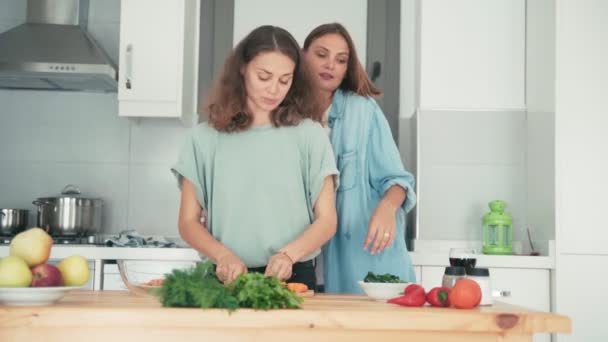 Dos mujeres jóvenes bastante caucásicas cocinando en la cocina brillante . — Vídeos de Stock