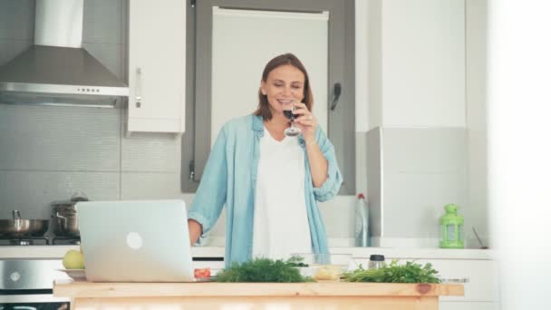 Jonge vrouw koken in de keuken tijdens het praten met vrienden via internet. — Stockvideo