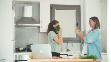 Mutfakta akıllı bir telefonla komik fotoğraflar çeken iki genç kadın..