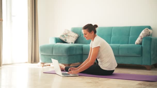 Atrakcyjna młoda kobieta uprawia jogę rozciągając jogę online w domu. — Wideo stockowe