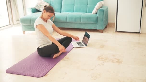 Aantrekkelijke jonge vrouw die yoga doet rekt yoga online thuis uit. — Stockvideo