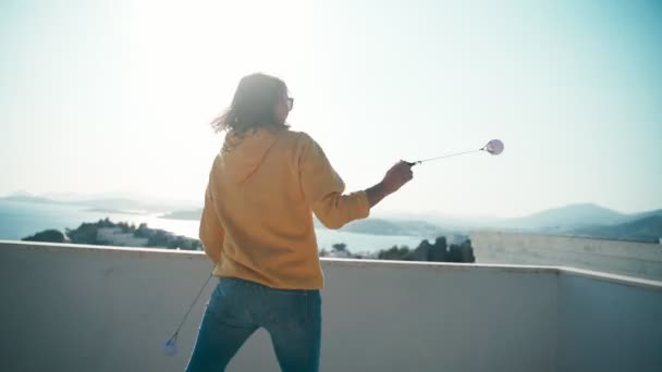 Jovem praticando poi bolas girando no telhado com vista para o mar — Vídeo de Stock